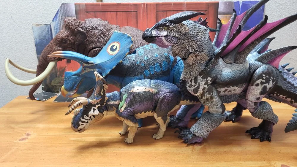 Figures in a left side view. All in a neutral pose with jaws closed. The mammoth is in the back, Torosaurus in front of it, and the Medusaceratops is in front of the Torosaurus. Kuraokami is in the front like the Medusaceratops, but behind it. In front of the reviewer's typical JW background.