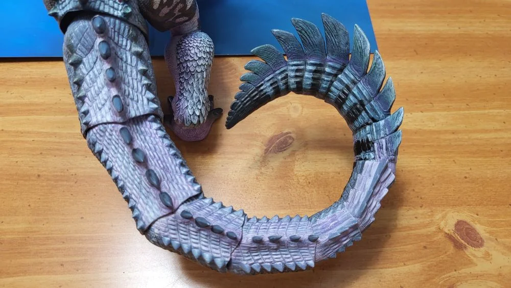 A look at the figure from the backside, and also above. A close up of the tail this time. Tail is curled on the right as much as possible. Figure is in front of the included package backdrop.