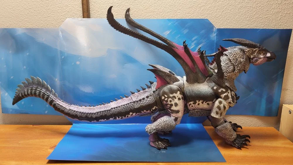 A complete right side view of the figure. Figure is in front of the included package backdrop. Jaw is closed. Tail is straightened out.